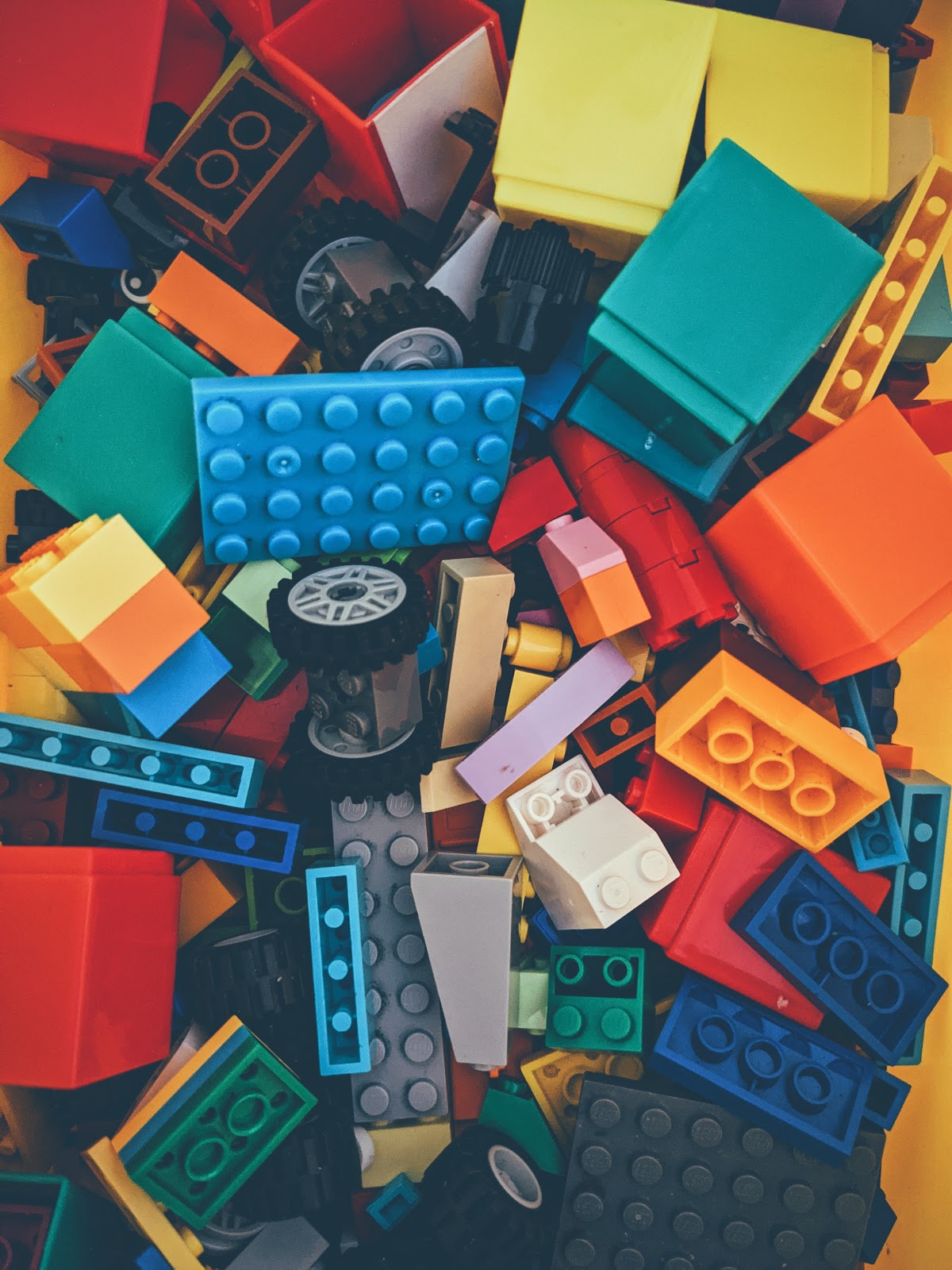 Lego-like building bricks, as well as wheels and axles of many colors lay in a jumbled pile.