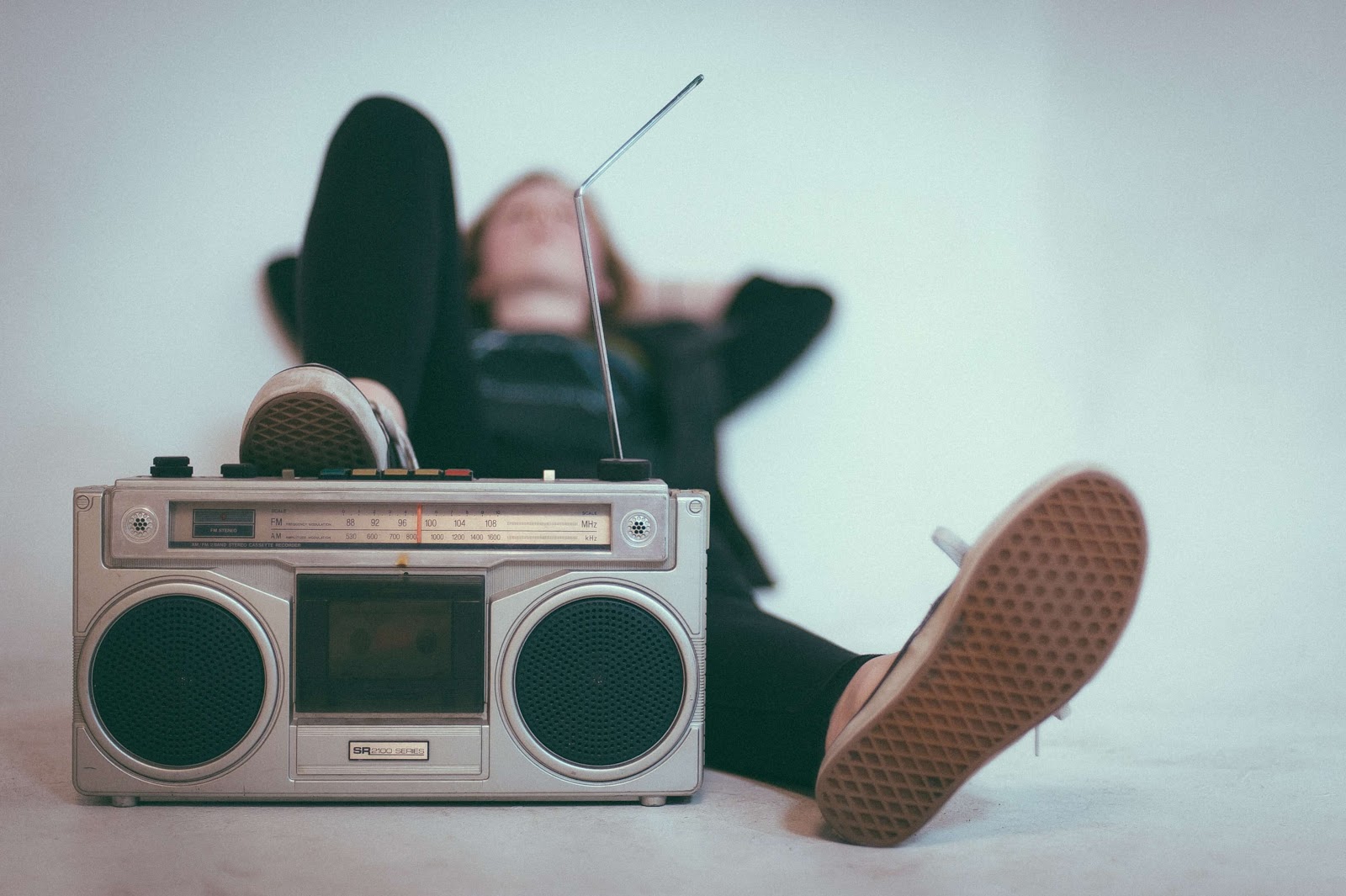 A person lying down with their foot rested on a portable radio