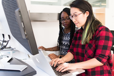 dos mujeres trabajando lado a lado en una computadora