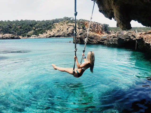 women on rope swing jumping in to ocean