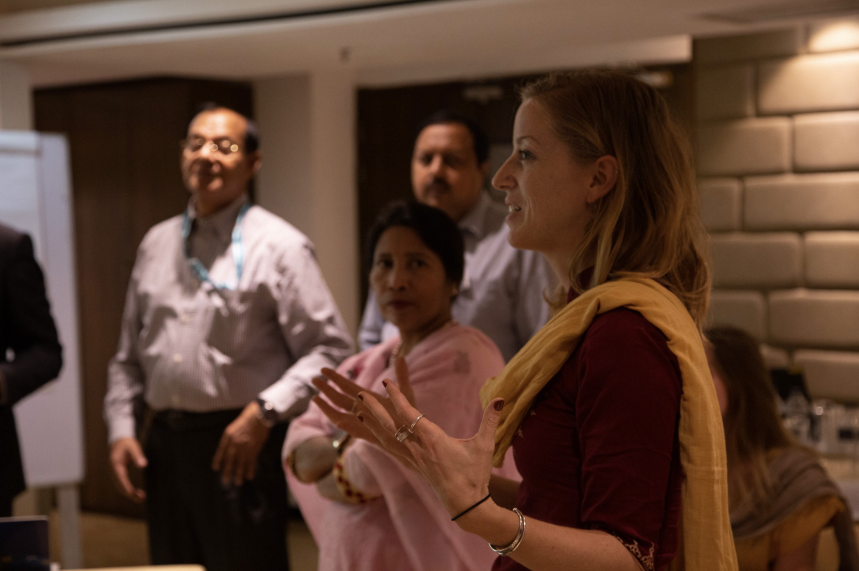 This image shows Mélody Braun speaking at an insurance workshop in Dhaka, Bangladesh. There are three people in the background listening, with 