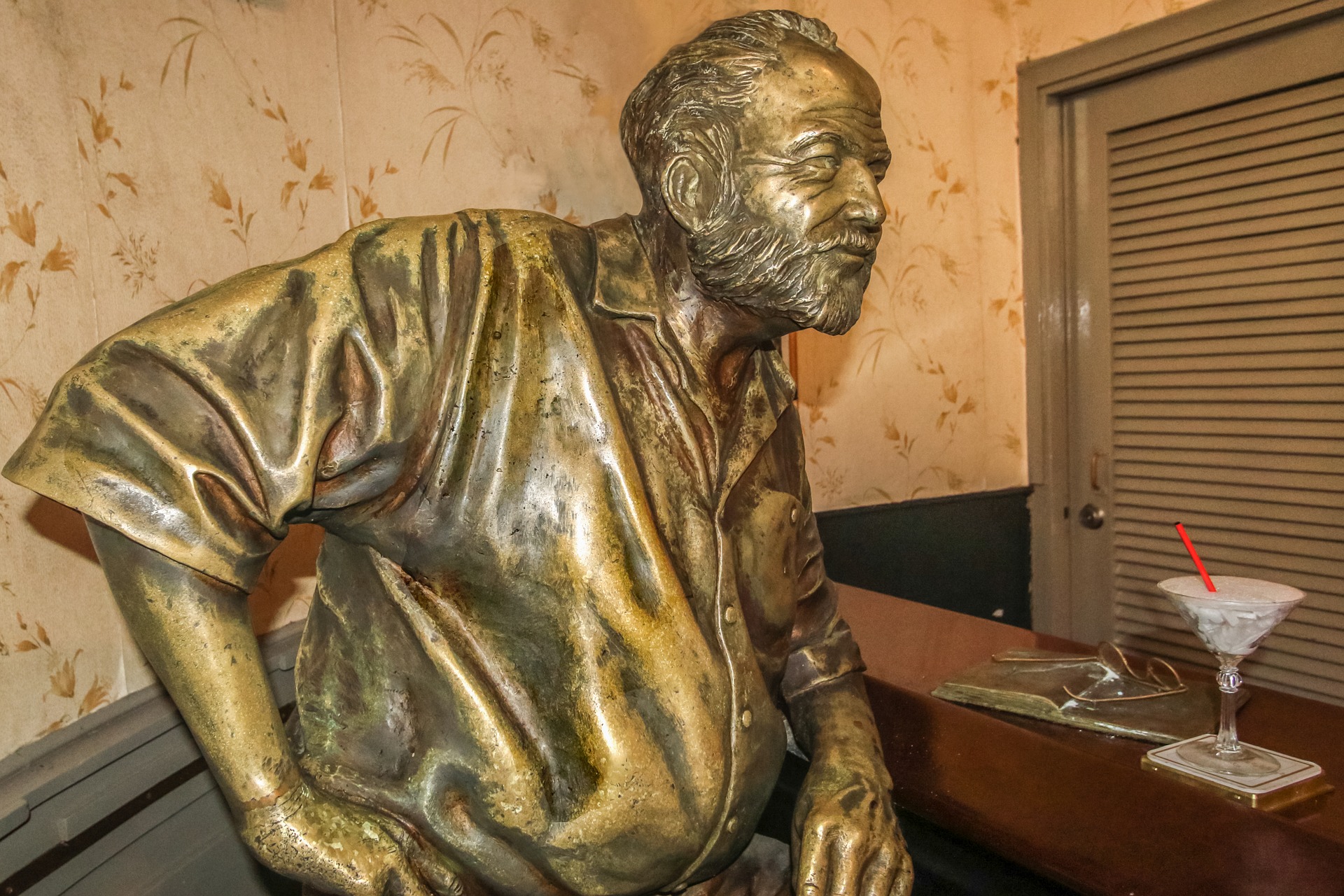 A bronze statue of Hemingway sitting in a bar