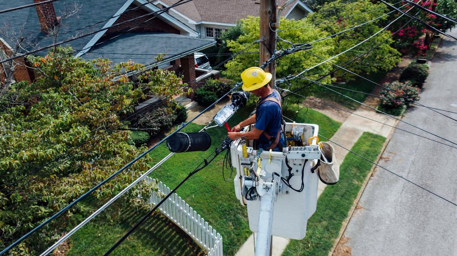 Technicien avec un casque jaune qui travaille sur une ligne électrique en hauteur