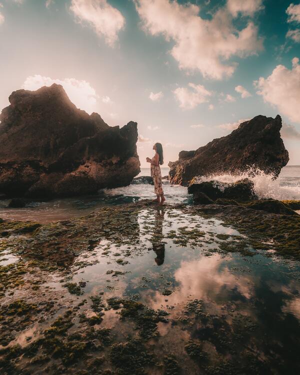 foto de uma mulher na água no meio de duas pedras