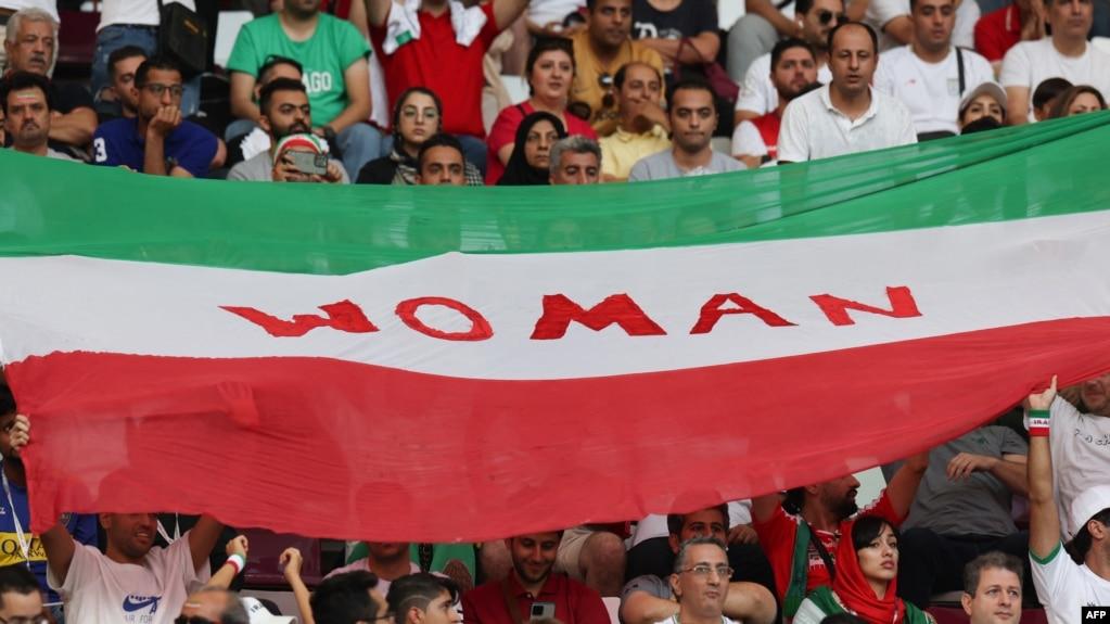 Cổ động viên Iran dâng cao quốc kỳ có dòng chữ "Phụ nữ" trên khán đài Sân vận động Quốc tế Khalifa ở Doha trong trận đấu vòng bảng đầu tiên tại World Cup, đang diễn ra ở Qatar, với đội tuyển Anh hôm 21/11.