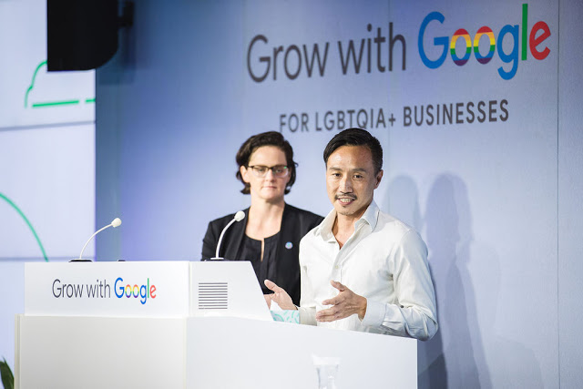 Two people stand behind a podium that reads "Grow with Google" with the Google logo in rainbows. Text behind them reads "Grow with Google for LGBTQIA+ businesses"