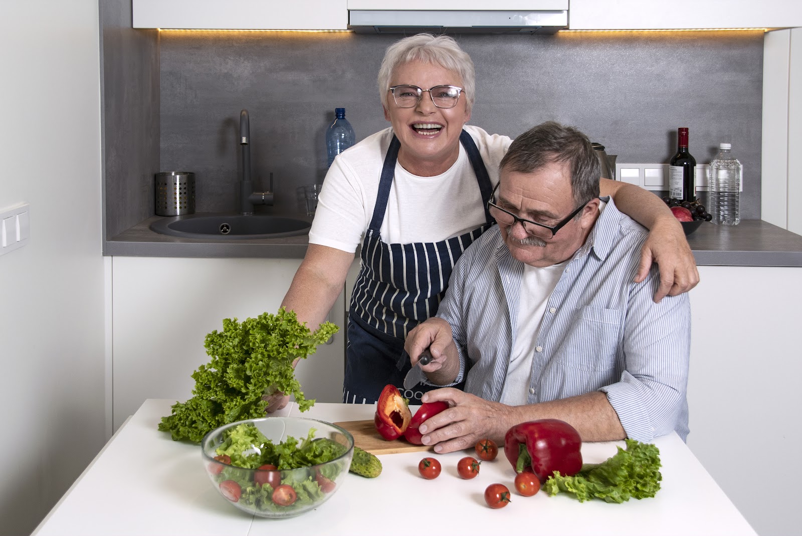 older woman and man cutting vegetables in kitchen