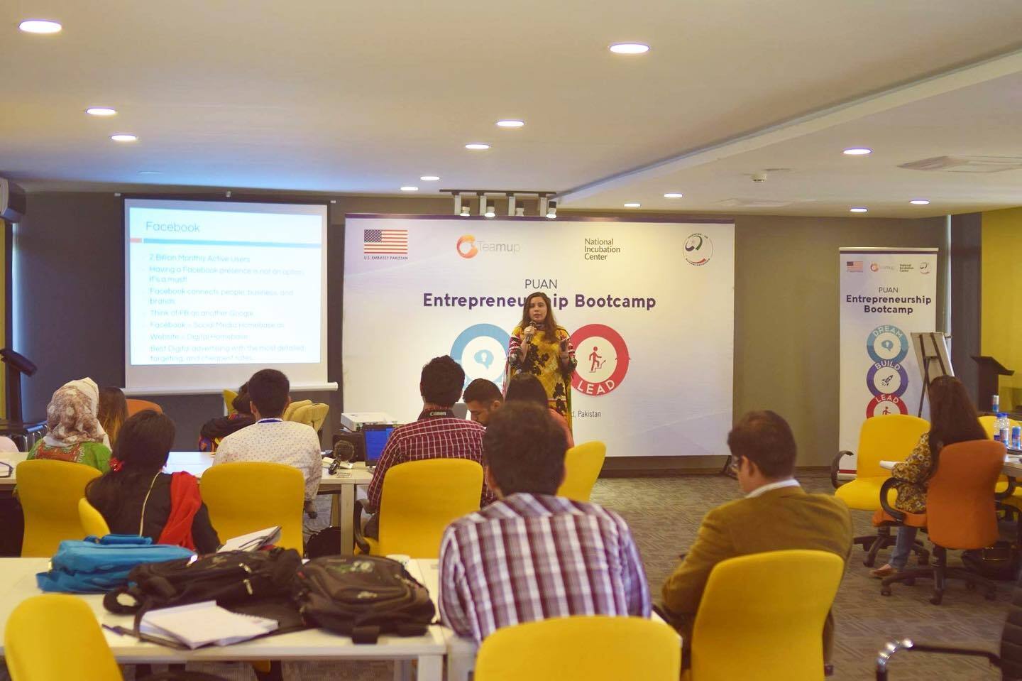 Women holding a presentation in front of many people.