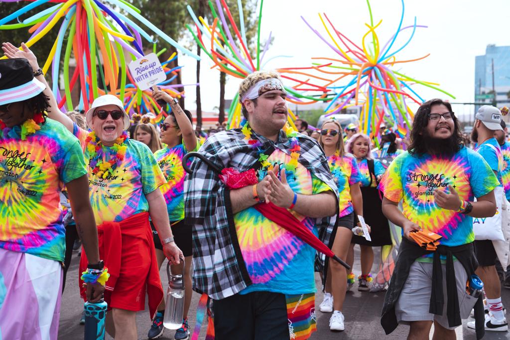 Group in tie-dyed attire marching in Phoenix Pride Parade