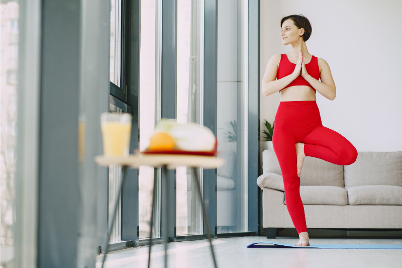femme sereine qui fait une posture de yoga chez elle