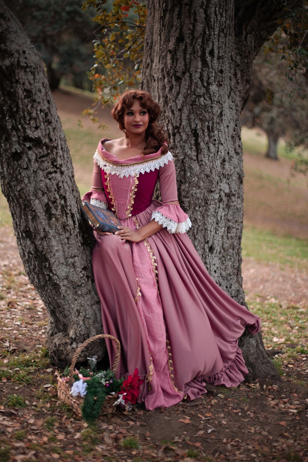 beauty and the beast belle cosplay. pink dress holding a book, curly brown hair