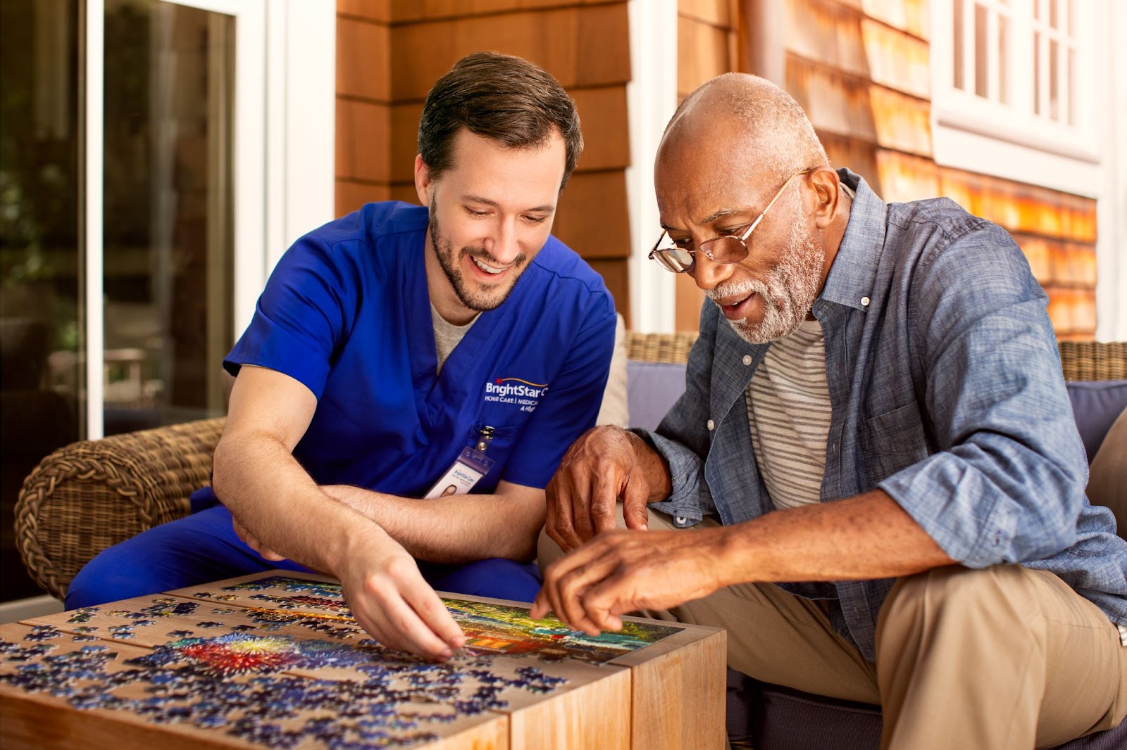 A Caretaker does a puzzle with a male senior
