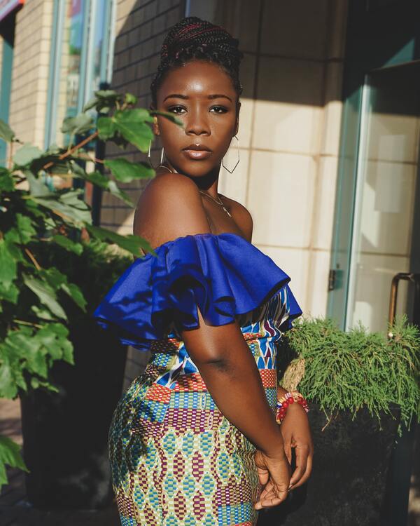 foto de uma mulher negra posando ao lado de plantas