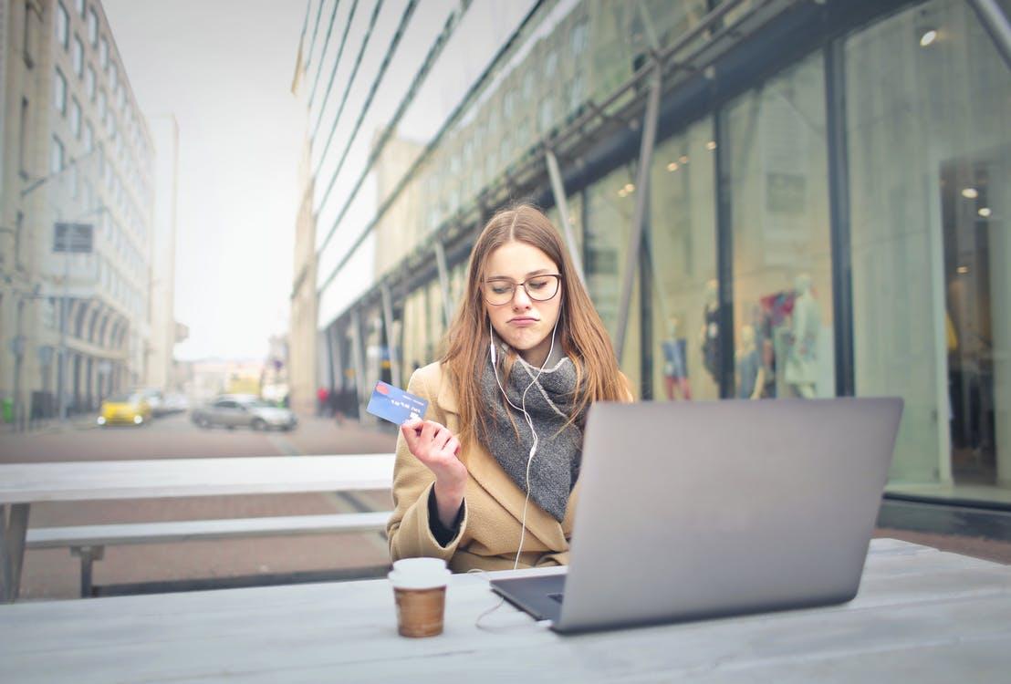 A woman holding her bank card while using her laptop