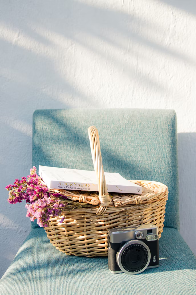 A basket with flowers, a book and a camera on a chair