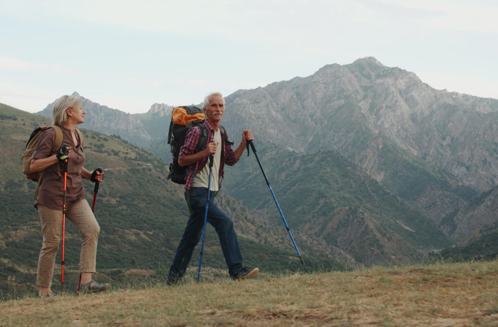 An active senior couple enjoying their mountain hike. Both of them with hiking backpacks and hiking poles