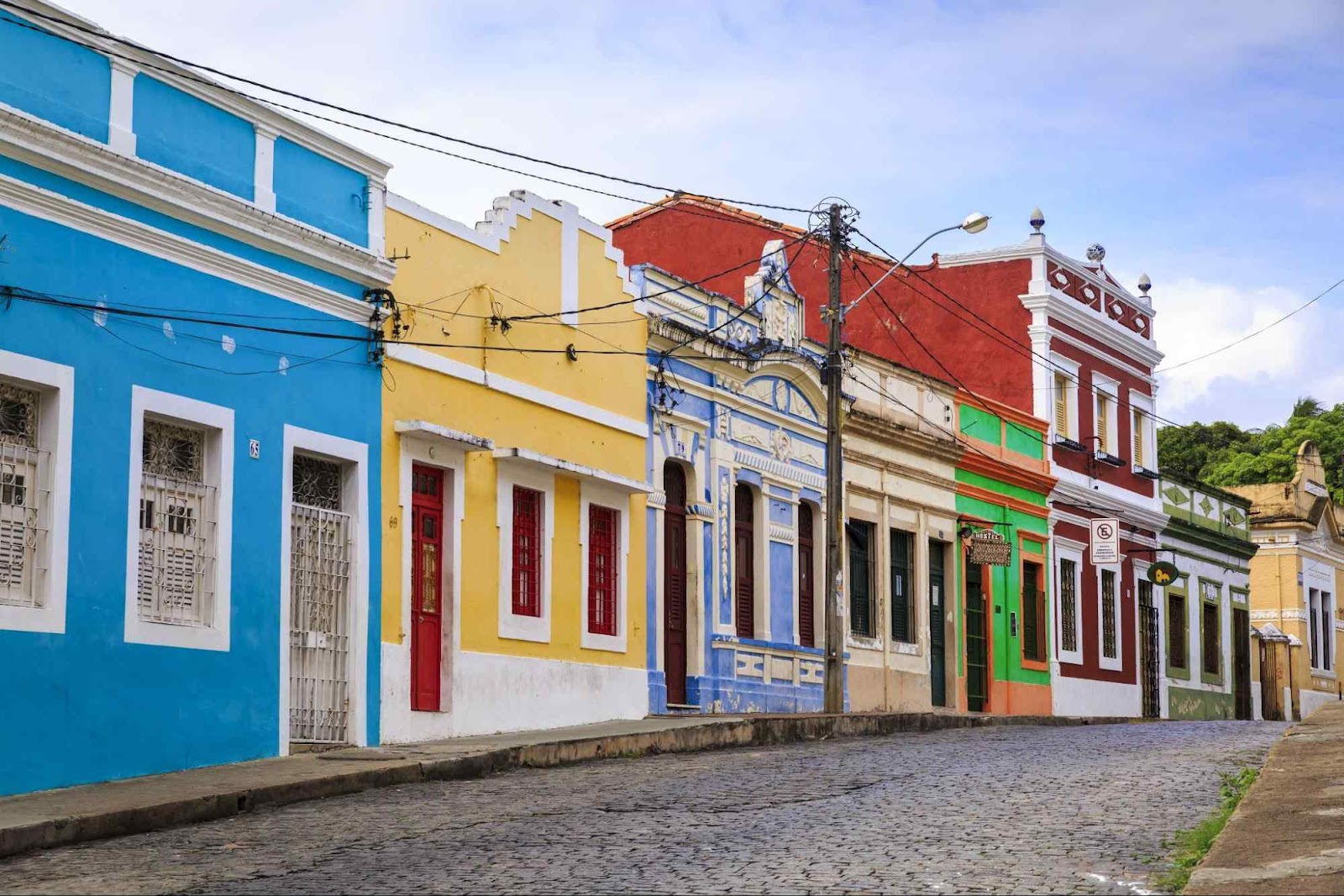Antigas casas do conjunto arquitetônico de Olinda. Elas estão enfileiradas em uma rua de paralelepípedo e têm fachadas estreitas e coloridas.
