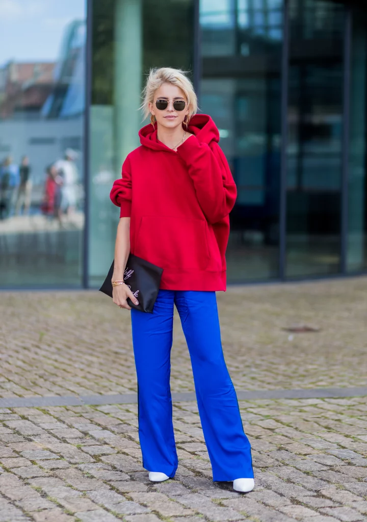 Blonde girl wearing red sweater with bright cobalt blue pants