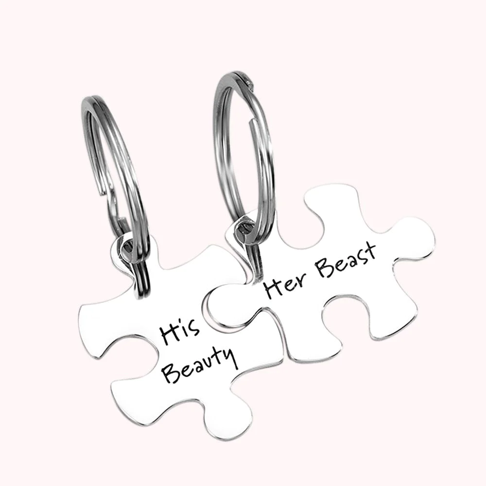 Deux portes-clefs, chacun en forme d’une pièce de puzzle allant l’une avec l’autre. Personnalisation par les mots “His Beauty” et “Her Beast”. 