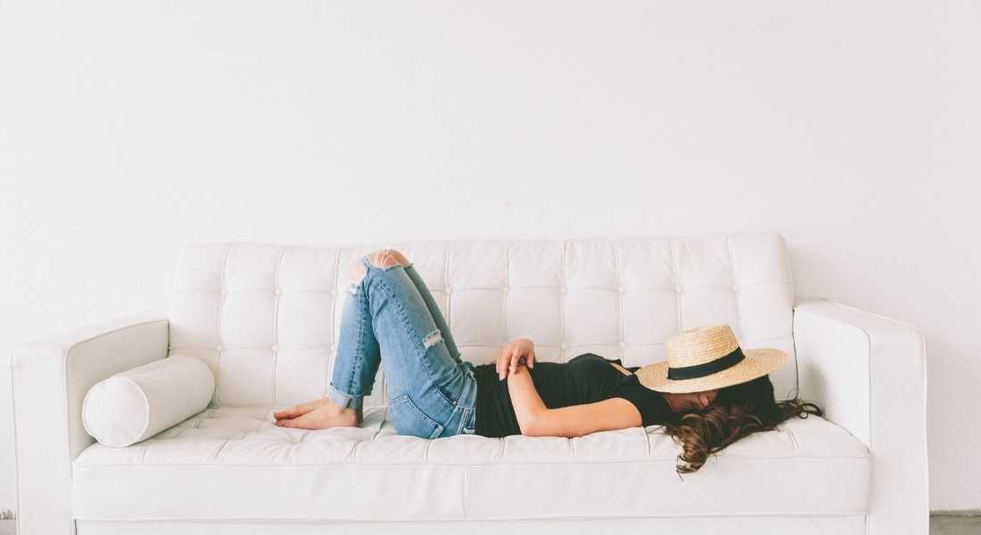girl laying on couch with hat over face