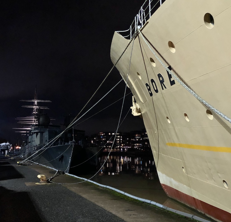 Sivukuva laivahostel S/S Boren keulasta yöllä ja takana Aurajoen maisemassa hohtavat valot ja Suomen joutsenen mastot. 