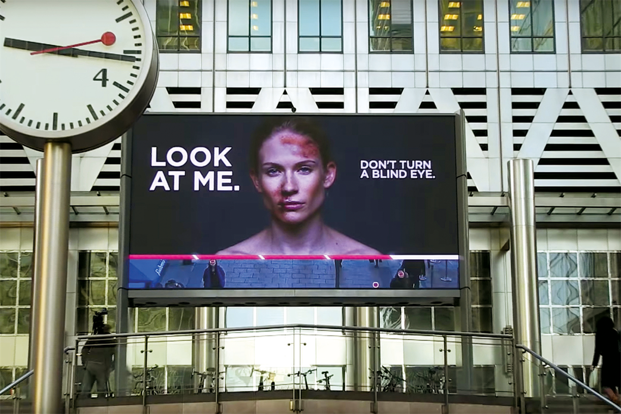 digital billboard showing a bruised woman with the text "Look at me" and "Don't turn a blind eye."