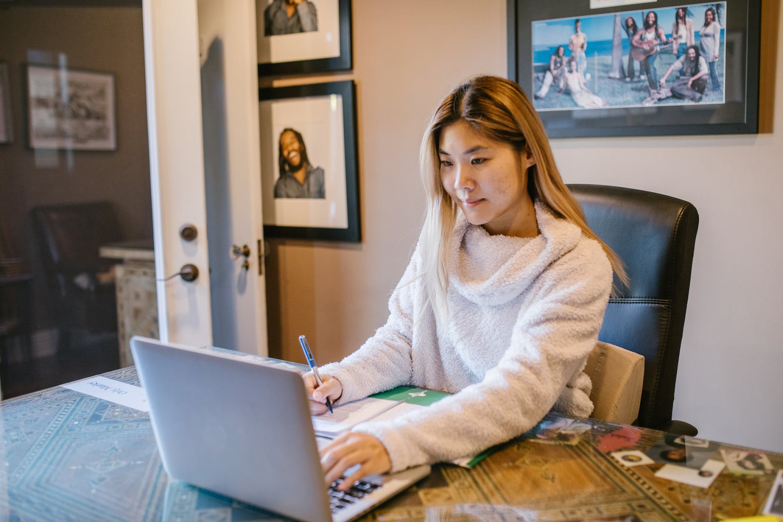 Woman sitting at a desk typing on her laptop and writing.