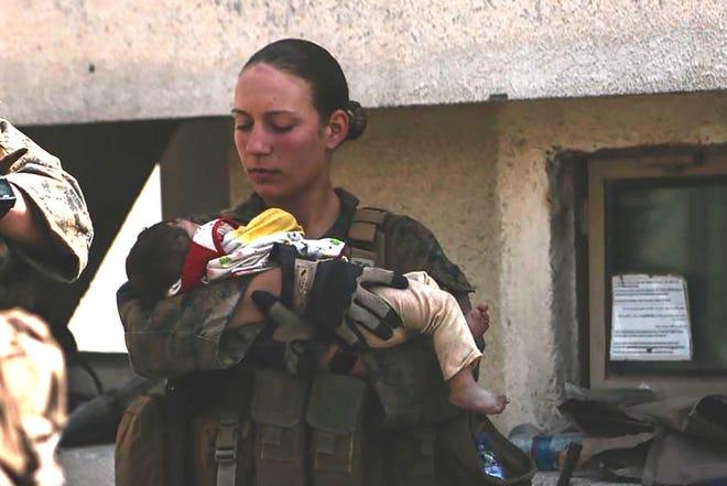 Marine Sgt. Nicole Gee, seen holding a baby at Kabul's airport, was one of the 13 U.S. service members killed in the Aug. 26 bombing in Afghanistan.