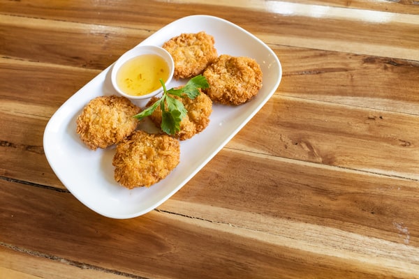 Five pieces of shrimp cakes on a white rectangular plate