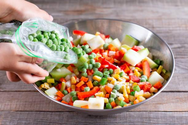 Frozen mix of vegetables and green peas in a bag on wooden table stock photo