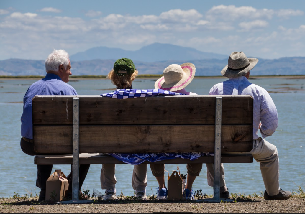 A group of people sitting on a bench Description automatically generated with medium confidence