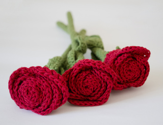 three red crochet roses on a white background