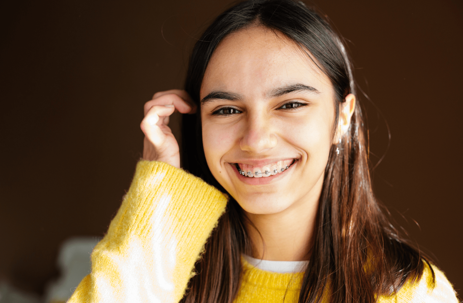 A teenage girl smiling and wearing metal braces