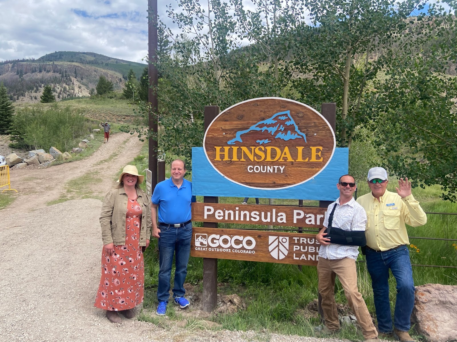 Governor Polis stands next to sign for Hinsdale County Peninsula Park.