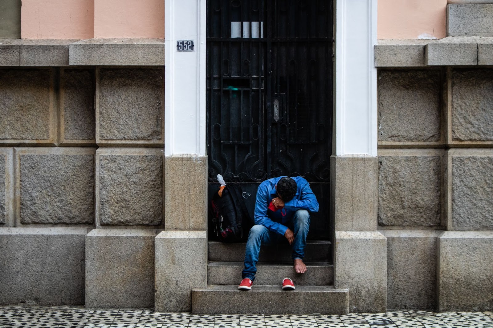 Photo of person sitting on building steps with a large backpack