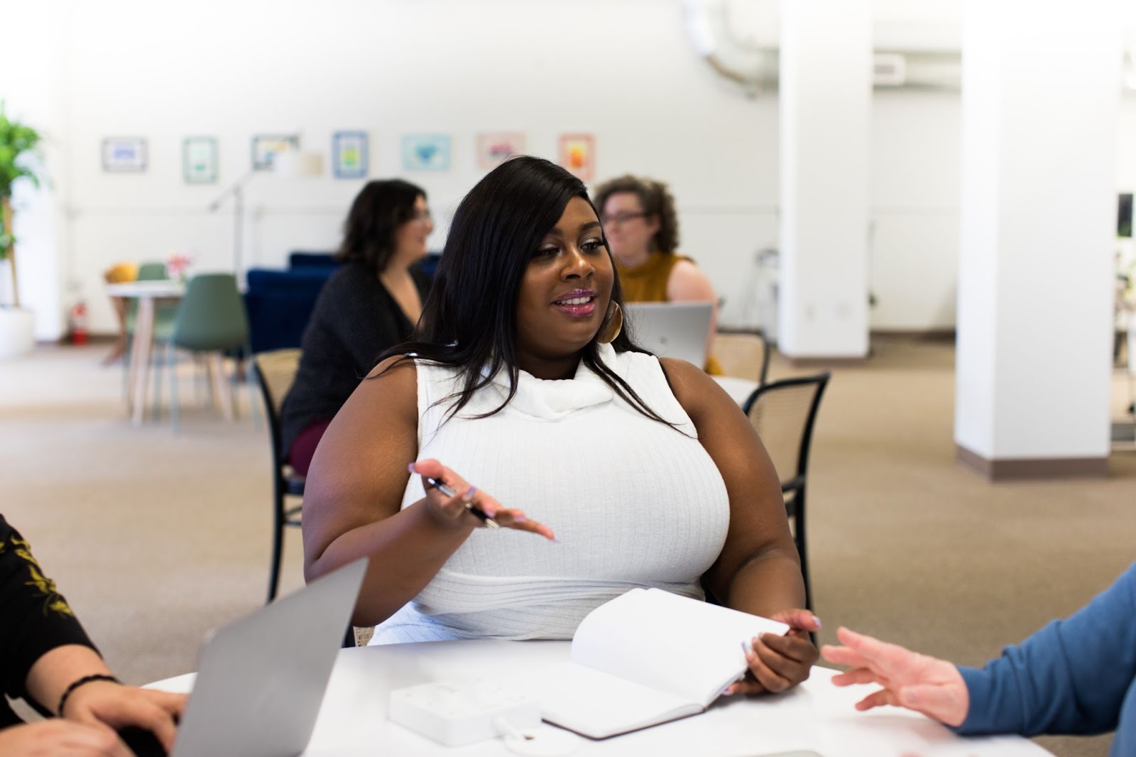 A woman in a workplace meeting smiles and gestures as if explaining something.