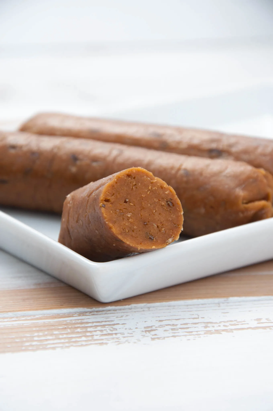 Three vegan sausages laid out on a white plate.