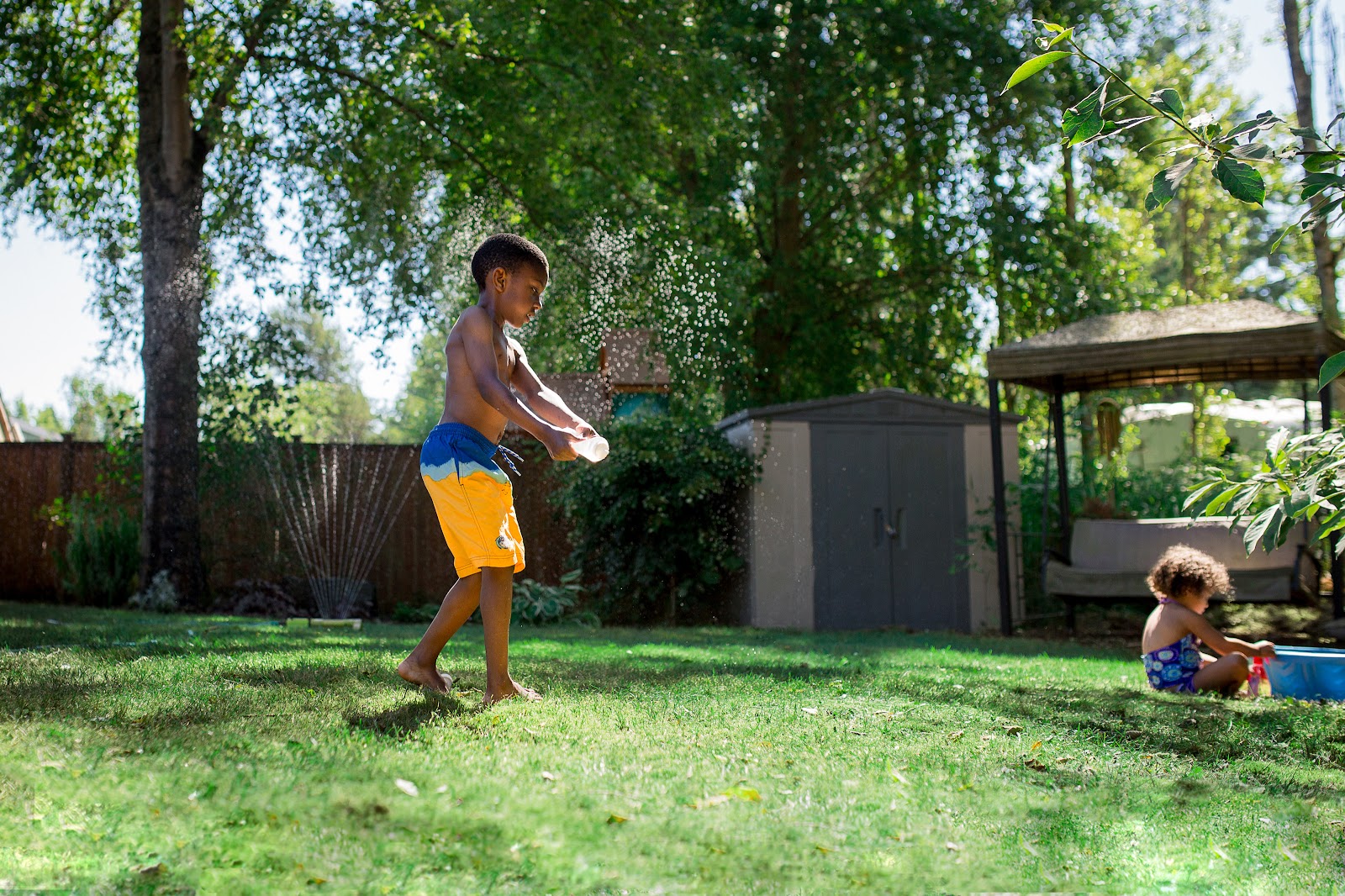 Boy playing in the lawn sprinkler at home