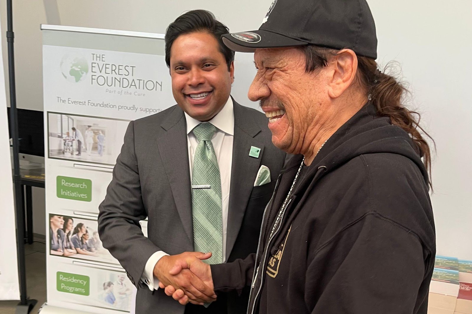 A picture of Dr. Michael Everest and Danny Trejo shaking hands and smiling at the ‘Bibles and Tacos’ event for homeless veterans.