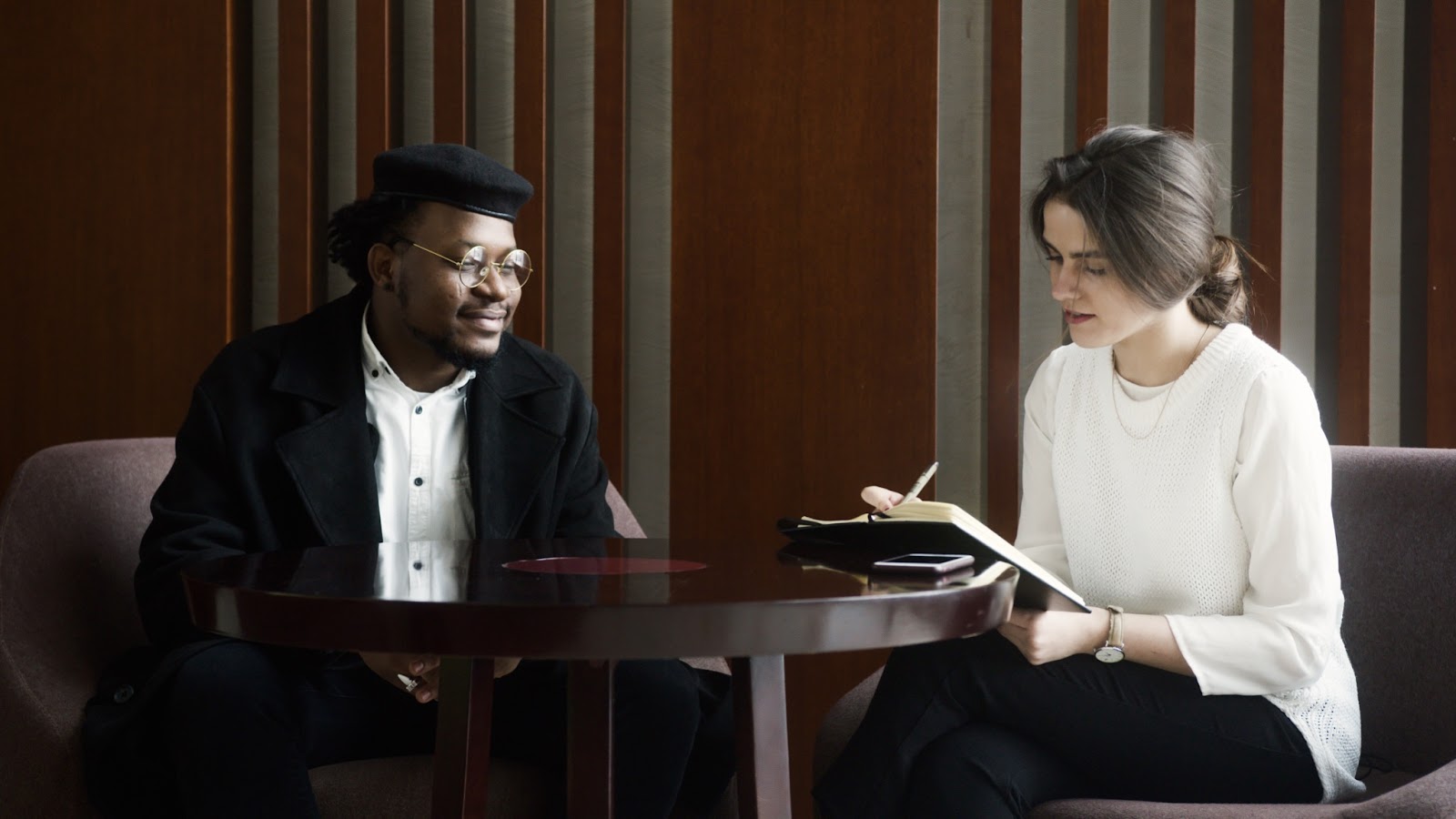 woman interviewing man in black hat