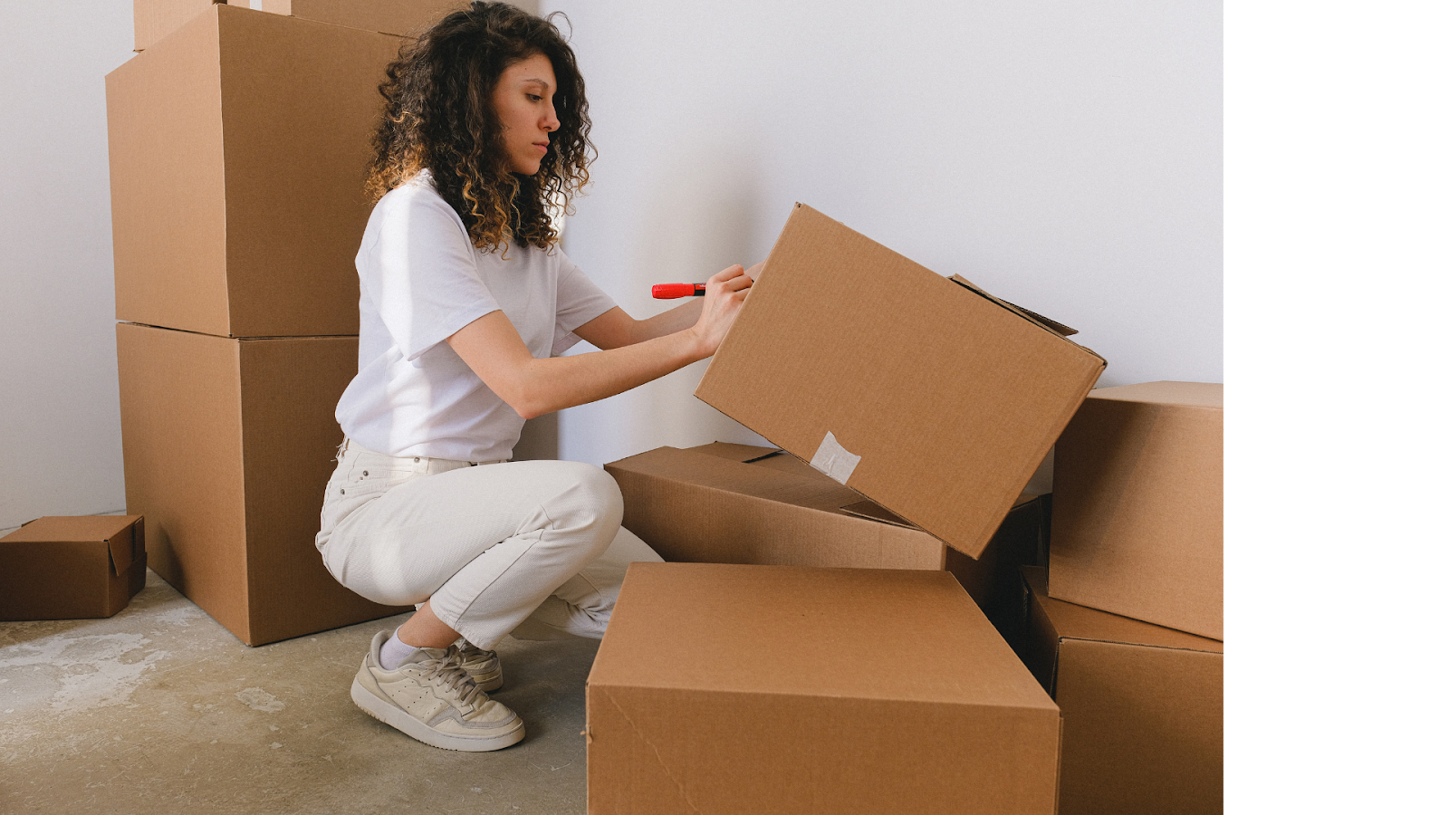 a woman in a squat position putting on label on boxes