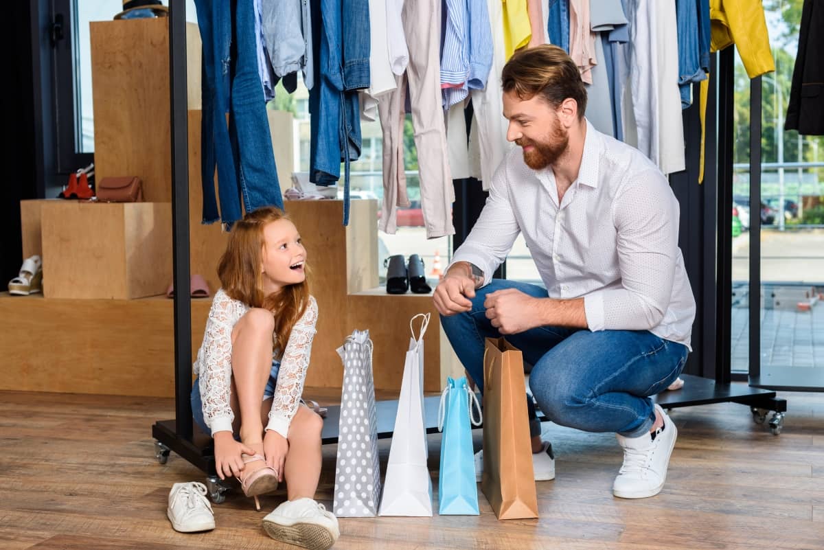 target audience - father and daughter smiling at each other while shopping for shoes