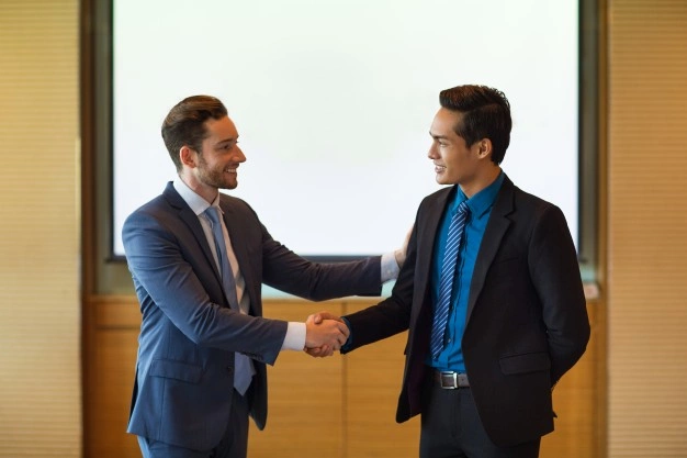 Tipos de empreendedores: homens de negócio sorrindo e apertando as mãos.