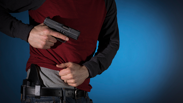 Man in red shirt removing gun from holster