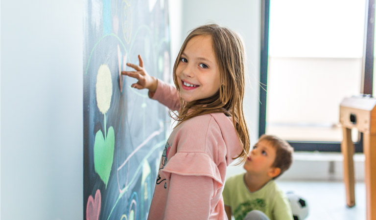 Children playing with a chalkboard wall in their playroom