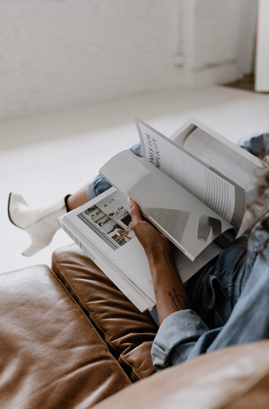 Woman sitting on a couch flipping through a book and thinking about the stories we tell ourselves