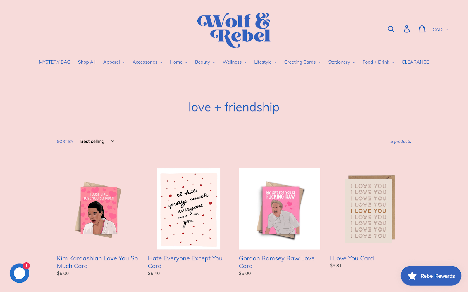 Valentine’s Day Gift Ideas–A screenshot from Wolf and Rebel’s “love + friendship” greeting cards product catalog page. There are 4 greeting cards visible that have cartoons of Kim Kardashian, Gordon Ramsey, and various messages on them. 