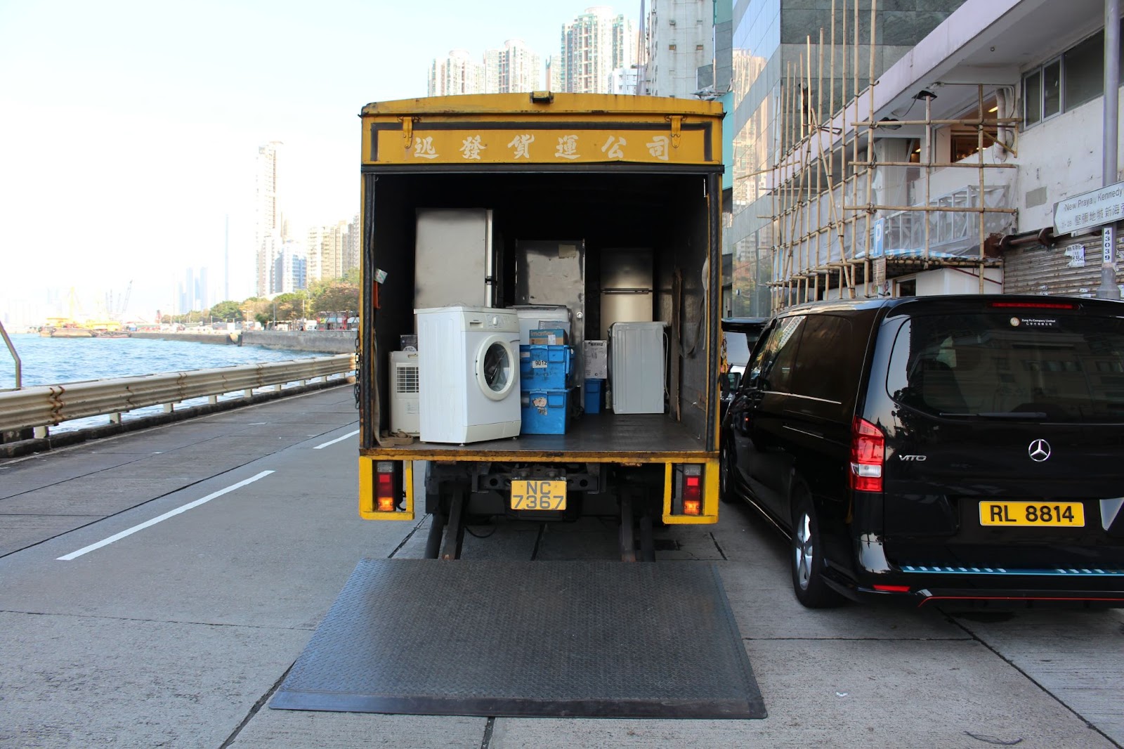 A liftgate fully lowered to the ground and attached to the back of a semi truck