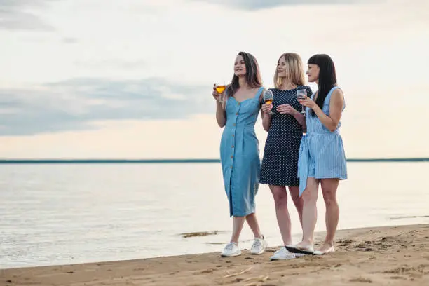 A group of women standing on a beach holding drinks
Description automatically generated