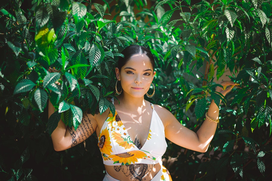 Uma linda senhora balançando o top de colheita perto de folhas verdes de verão